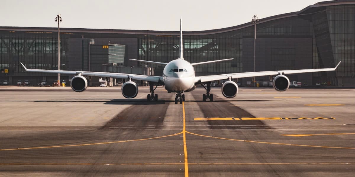 A wide-body airliner facing the camera on a taxiway in front of a terminal